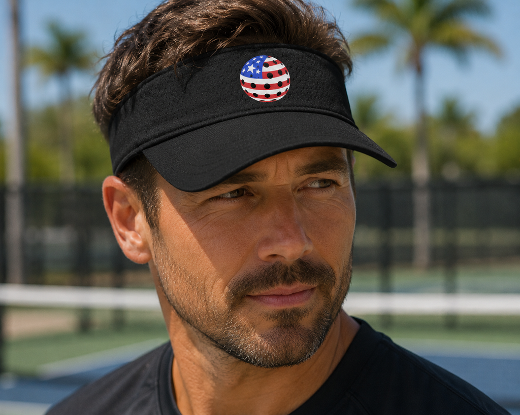 Man wearing a black visor with a USA pickleball design on a pickleball court